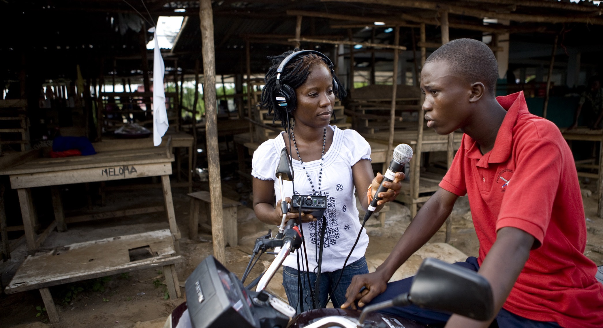 Tetee Gebro interviewing a man with a microphone and recording equipment in Liberia.